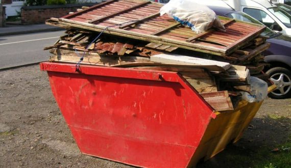 Dangerously overloaded red skip bin.