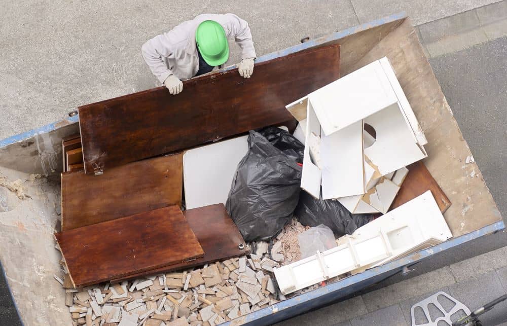 worker depositing rubbish in in skip bin