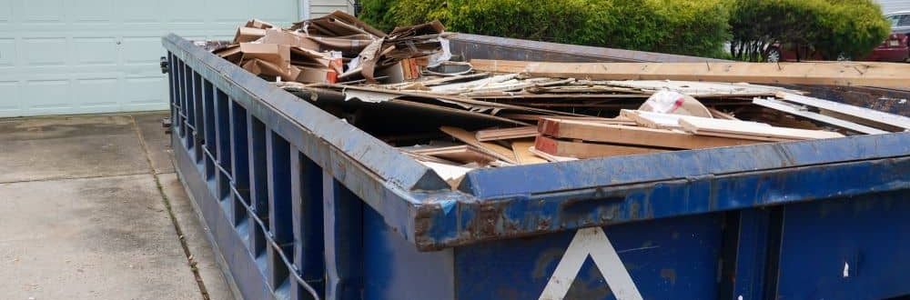 Skip on the driveway filled with debris.