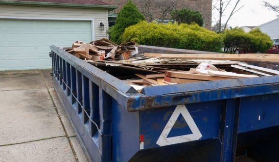 Skip on the driveway filled with debris.