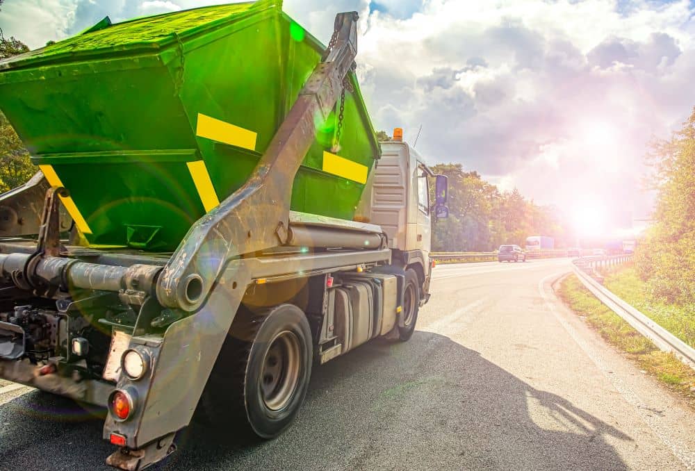 Full skip bin on the back of a truck driving to the waste management facility.