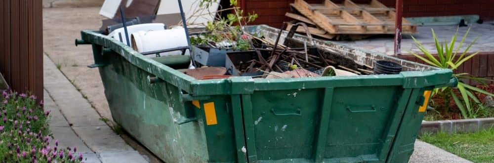 Hired skip bin on the yard filled with household rubbish.