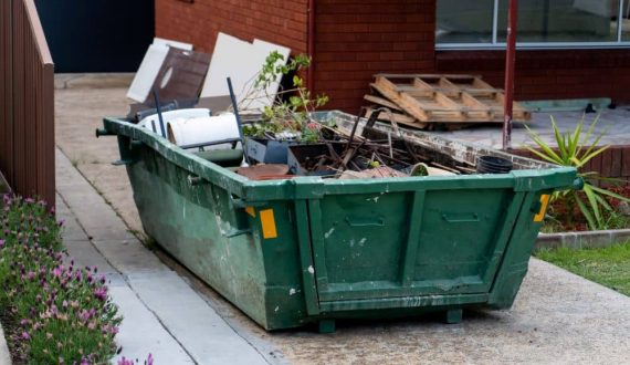 Hired skip bin on the yard filled with household rubbish.