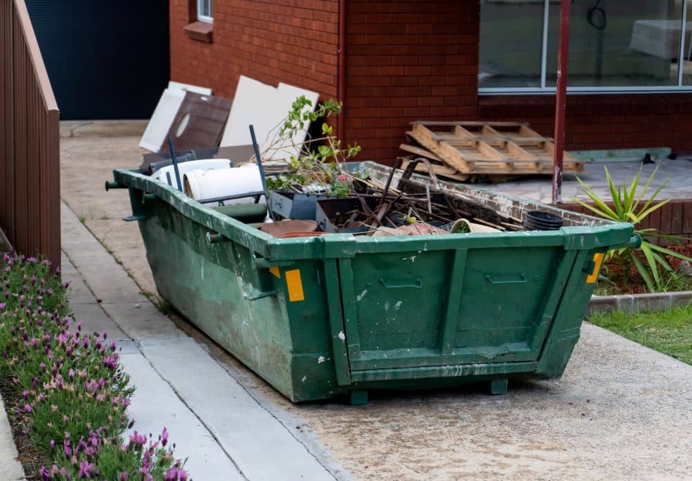 Hired skip bin on the yard filled with household rubbish.